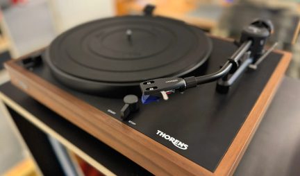 Schwarzer Thorens-Plattenspieler mit Holzfinish, Tonarm und Plattenteller, in Schrägansicht