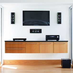 Hjemmebiografsystem med lyst træmøbel, fladskærms-tv, to sorte højttalertårne og en sort subwoofer