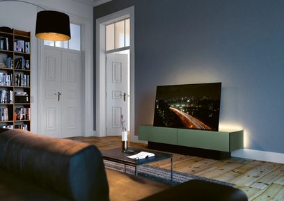 Lavt mørkegrønt og matsortt TV-møbel med døre, skuffe, hylder, fladskærm, moderne stue, parketgulv, bogreol, sort pendellampe