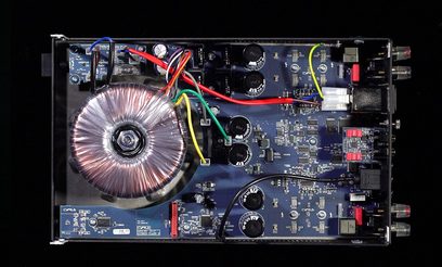 Indvendigt billede af en Cyrus ONE HD stereo hi-fi forstærker, der viser printplader, elektroniske komponenter og en toroidaltransformator