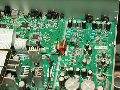 Grønt printplade med mange elektroniske komponenter, kondensatorer og stik, tæt på indersiden af en Marantz NA-8005 elektronisk enhed