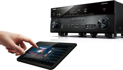 Yamaha RX-A740 sort home cinema-forstærker set forfra, LCD-skærm, knapper og drejeknap, hånd der styrer appen på tablet