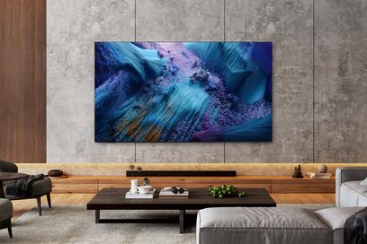 Großformatiger schwarzer Fernseher mit ultrafinem Metallrahmen und glatter Glasoberfläche, frontal an einer Sichtbetonwand montiert