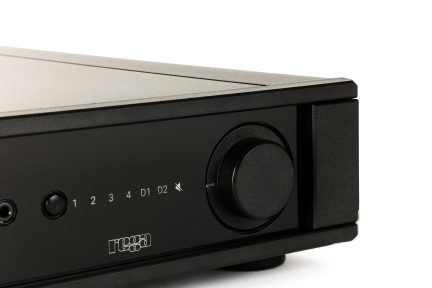 Close-up view of a black front panel with a circular button, numbers, letters, a mute icon, and a "rega" logo