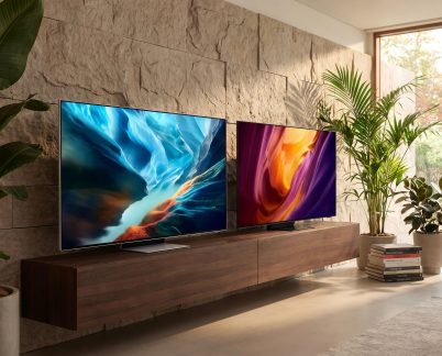 Two flat-screen televisions on a suspended wooden cabinet in a contemporary living room with green plants