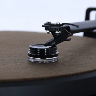 Sada pro nastavení a čištění Enova HIFI GVS 20, detailní pohled na gramofonovou kazetu na černém a průhledném kruhovém držáku, hnědý talíř v pozadí