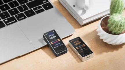 Dois caixas de som metálicas em preto e prata, tela colorida PCM 768K, botões sensíveis ao toque e porta USB-C, vista em ângulo