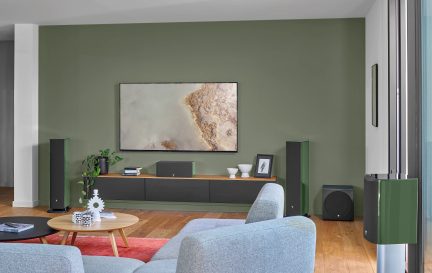 Modernes Wohnzimmer, olivgrüne Wände, heller Parkettboden, graue Sessel, Couchtisch aus Holz, reduzierte Dekoration