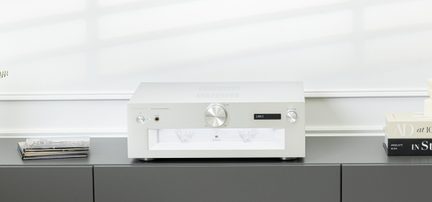 Amplificatore stereo in alluminio argento spazzolato, vista frontale, grande manopola centrale, display a destra, presa per cuffie, VU-meter