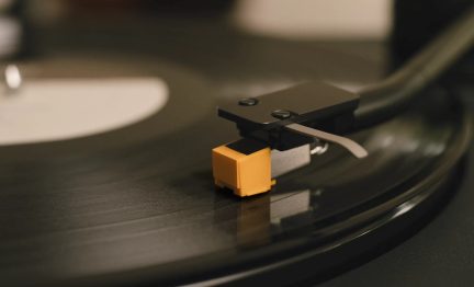 Siyah plak çalarken, siyah disk üzerinde sarı elmas iğneli pikap kafasının yakın planı