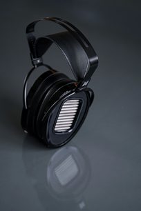 Sluchátka Hifiman Arya Unveiled s otevřenou konstrukcí, oválnými černými náušníky s stříbrným mřížkováním, perforovaným černým obloukem, pohled ze šikma