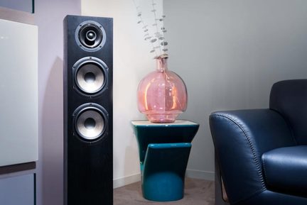 Cassa acustica a colonna nera con rivestimento in legno, dotata di tre altoparlanti circolari metallici, vista da tre quarti frontale