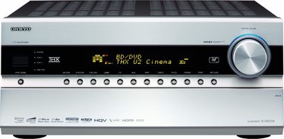 Fronten af Onkyo TX-NR3008 hjemmebiografsforstærker, sølvfarvet front med blå skærm, knapper og drejeknap, porte i bunden