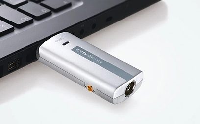 Stříbrná USB klíčenka Elgato EyeTV Diversity, konektor USB samec, pohled shora a z boku, položená na černé klávesnici