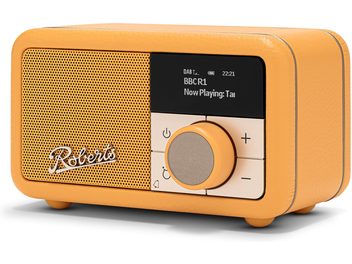 Three-quarter front right view of the Roberts Revival Petite 2 table radio in yellow with a grained faux leather finish, featuring a wide perforated metal speaker grille with logo, a black digital display, and a large central circular knob surrounded by buttons.
