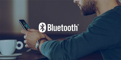 Billedet viser en mand, der bruger en smartphone til at interagere med Bluetooth-appen på en mørk baggrund