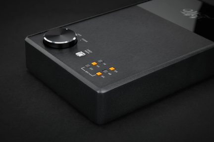DAC audio nero in metallo spazzolato con manopola del volume e spie arancioni, vista dall'alto