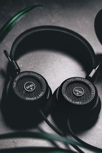 To åbne hovedtelefoner fra Grado, en SR80x og en SR325x, sorte med metalgittere, på en mørkegrå baggrund