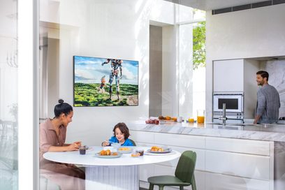 Televizor Samsung QE55Q95T 2020 v moderním obývacím pokoji zobrazující rodinu u stolu před přírodní krajinou na obrazovce