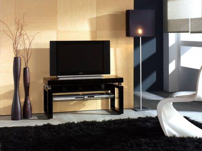 Černý a dřevěný TV stolek s policí na audio-video zařízení, černé sloupové reproduktory, stojací lampa a bílá pohovka
