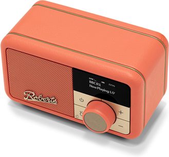 Stolní rádio Roberts Revival Petite 2 v oranžové barvě v obdélníkové krabici potažené zrnitou umělou kůží s zaoblenými hranami a zlatými lemováními, přední strana s perforovanou mřížkou reproduktoru, černým displejem a velkým kruhovým béžovým tlačítkem, pohled zepředu v tříčtvrtečním úhlu shora
