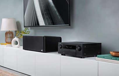 Denon AVC-X3700H sort hjemmebiografsforstærker, set forfra, placeret på hvidt møbel med sort fotoramme og hvid vase