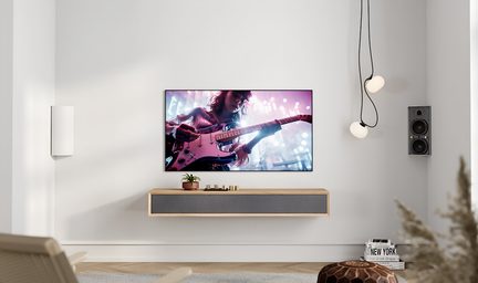 Wohnzimmer, Frontalansicht, wandmontierter Fernseher, schwebende Konsole aus hellem Holz mit grauer Stofffront, grauer Wandlautsprecher