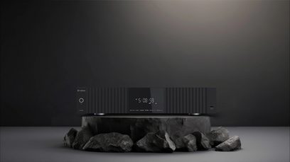 Reproductor multimedia Zidoo UHD8000, vista frontal, caja rectangular negra, pantalla central luminosa, colocado sobre una base rocosa