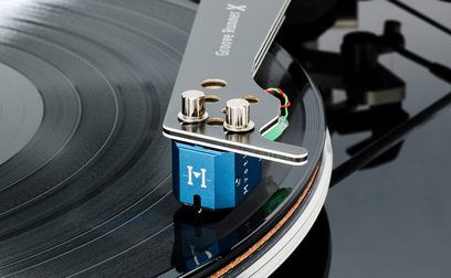 Skråt nærbillede af en sort Vertere Acoustics Pack DGX Mystic II hi-fi pladespiller med sort, blank vinylpladetallerken, slank tonearm i satin-gråt metal med tre runde udskæringer og blåanodiseret pickup