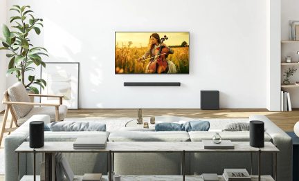 Czarny soundbar z subwooferem i bezprzewodowymi głośnikami przed telewizorem ściennym w nowoczesnym salonie