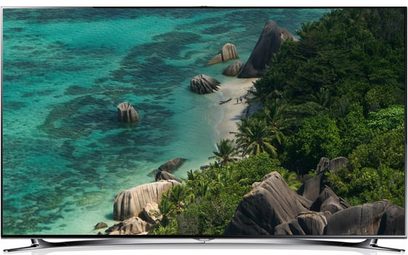 Televisore Samsung UE46F8000 che mostra una spiaggia tropicale con rocce, vegetazione e un mare turchese