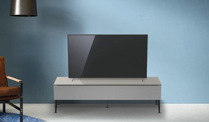 Lysegrå TV-møbel Just By Spectral Bravo JSB1624 set forfra, med en sort fladskærm ovenpå og en hængelampe ovenover