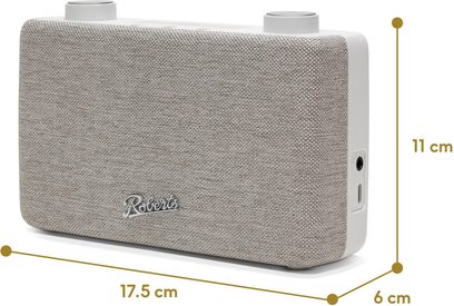Radio de mesa Roberts Play 11 color crema, vista desde tres cuartos delantera derecha, carcasa de plástico blanco roto con frontal de tela beige texturizada, dos ruedas circulares en la parte superior, logo metálico en el frontal y conexiones laterales
