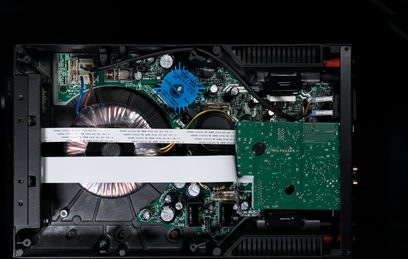 Amplificador hi-fi estéreo Cyrus 6 DAC QXR, vista interior mostrando placas de circuito impresso verdes, componentes eletrônicos e transformador toroidal