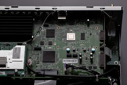 Grüne Leiterplatte mit elektronischen Bauteilen, Prozessoren und Anschlüssen in einem geöffneten schwarzen Metallgehäuse