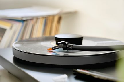 Juoda vinilinė plokštelių žaidyklė su galvute ir adatėle, ant kurios padėta vinilinė plokštelė, vaizdas iš viršaus