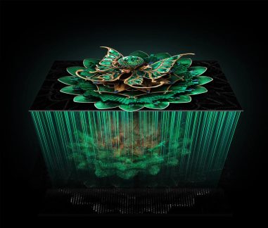 Digital skulptur i form av en stiliserad smaragdgrön blomma prydd med gyllene metalliska kanter, placerad på ett slätt svart block varifrån smaragdgröna ljusstrålar strålar ner, sedd ur fågelperspektiv