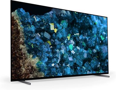 Sony XR83A80L fjernsyn med bred skærm, set fra trekvart vinkel, viser blå krystaller, sort ramme, metalfødder