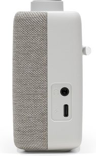 Vista lateral de una radio de mesa Roberts Play 11 en color crema con acabado mate, panel de altavoz en tela gris melange, puerto USB-C y toma de auriculares integrados, y rueda metálica al ras
