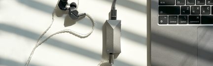 Sortøjs højttalere i sort med hvid flettet kabel, grå lydtilpasning, bærbar computer-tastatur i grå