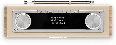 Radio til bordet Roberts Rambler Uno i cremefarve med glat plastikfront og lyse træsider, set forfra, med centralt sort digitalt display, to store runde knapper i børstet metal, række med seks rektangulære knapper ovenover og en sammenfoldet teleskopantenne på toppen
