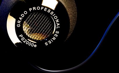 Åbne hi-fi hovedtelefoner Grado PS2000E, nærbillede af gylden metalrist på sort ørekop, hvidt logo "GRADO PROFESSIONAL SERIES PS2000e"