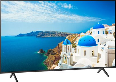 Panasonic TX-55MX950E-fladskærm, der viser et luftfoto af en middelhavsk kystlandsby med hvide bygninger og blå kupler