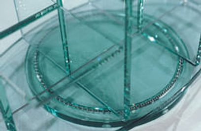 Spiraltrappe i glas med gennemsigtige trin og rækværk, set oppefra i et skråt perspektiv