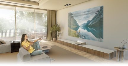 Moderne stue med grå sofa, træ-sofabord, beige gardiner, grøn plante, vægprojektion af bjerglandskab