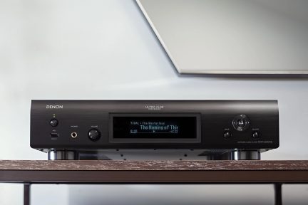 Odtwarzacz sieciowy audio Denon ULTRA AL32, widok z przodu, cyfrowy wyświetlacz pokazujący "The Naming of Thir", przyciski i złącza na przednim panelu z szczotkowanego aluminium