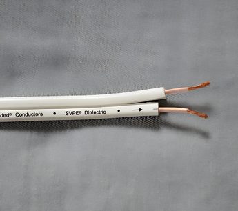 Hvid SVPE dielektrisk kabel fra Conductors-mærket, med sorte markeringer og blottede kobberspidser, på ensfarvet grå baggrund