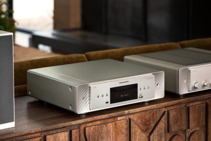 Marantz CD 60 CD-Player in Silber mit schwarzem Frontdisplay, Tasten und Kopfhöreranschluss, Dreiviertelansicht auf einem Holzmöbelstück