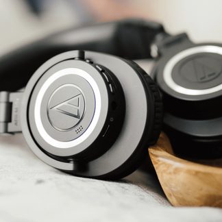 Sluchátka v černé a šedé barvě, boční detailní pohled, kulaté náušníky s centrálním logem, polstrované polštářky