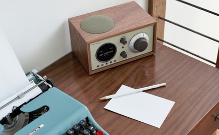 Træbordradio i brun, beige front med stor knap, rund skærm og højttalergitter ovenpå, skråt set